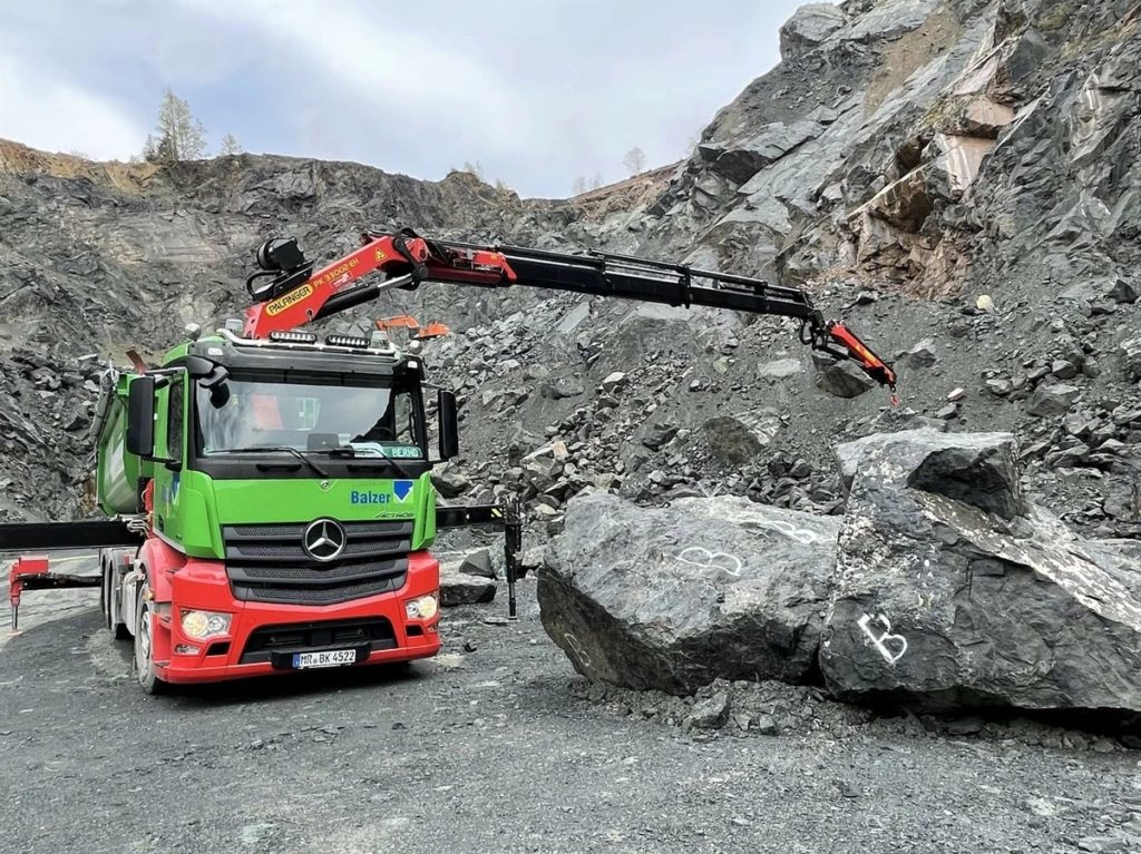 Tahač se sedlovým návěsem si sám naloží kamenivo pomocí hydraulického jeřábu Palfinger.