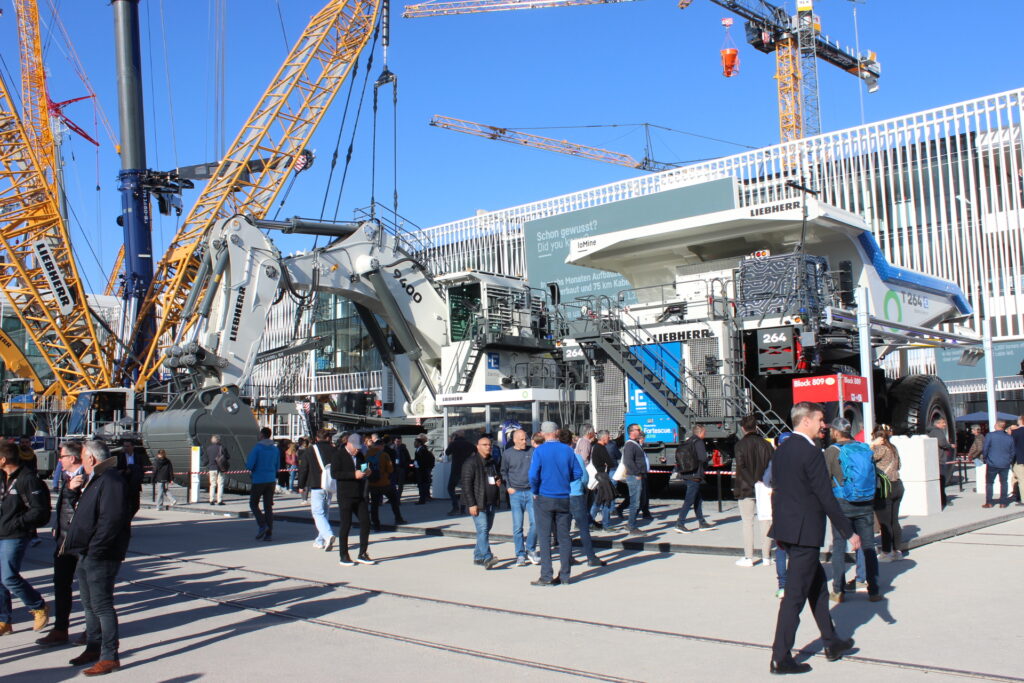 Elektrický nákladní vůz Liebherr T 264 Battery Electric a vedle stojící elektrický bagr 9400 